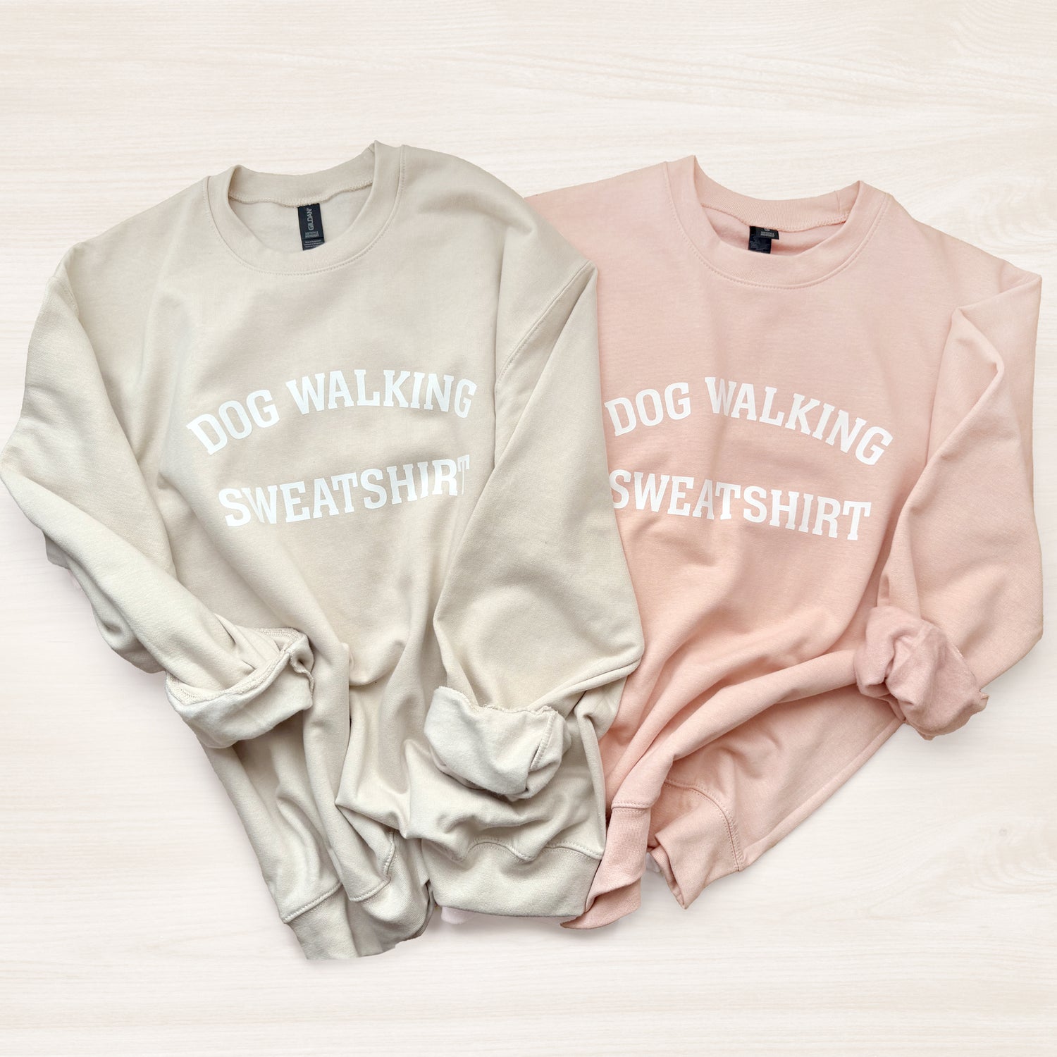 Two sweatshirts, one beige and one pink, with 'DOG WALKING SWEATSHIRT' text on a light background.